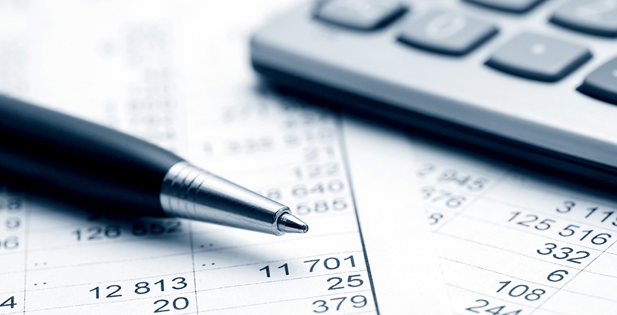 Ein Stift und ein Taschenrechner auf mehreren Dokumenten mit Zahlen