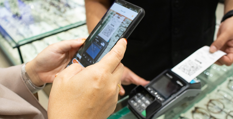 A customer scanning a QR code with a smartphone for cashless payment at a store